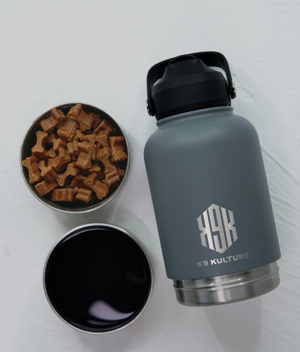 Grey ThermoACTIVE insulated dog water bottle displayed with dual compartments—one filled with water, one with treats.