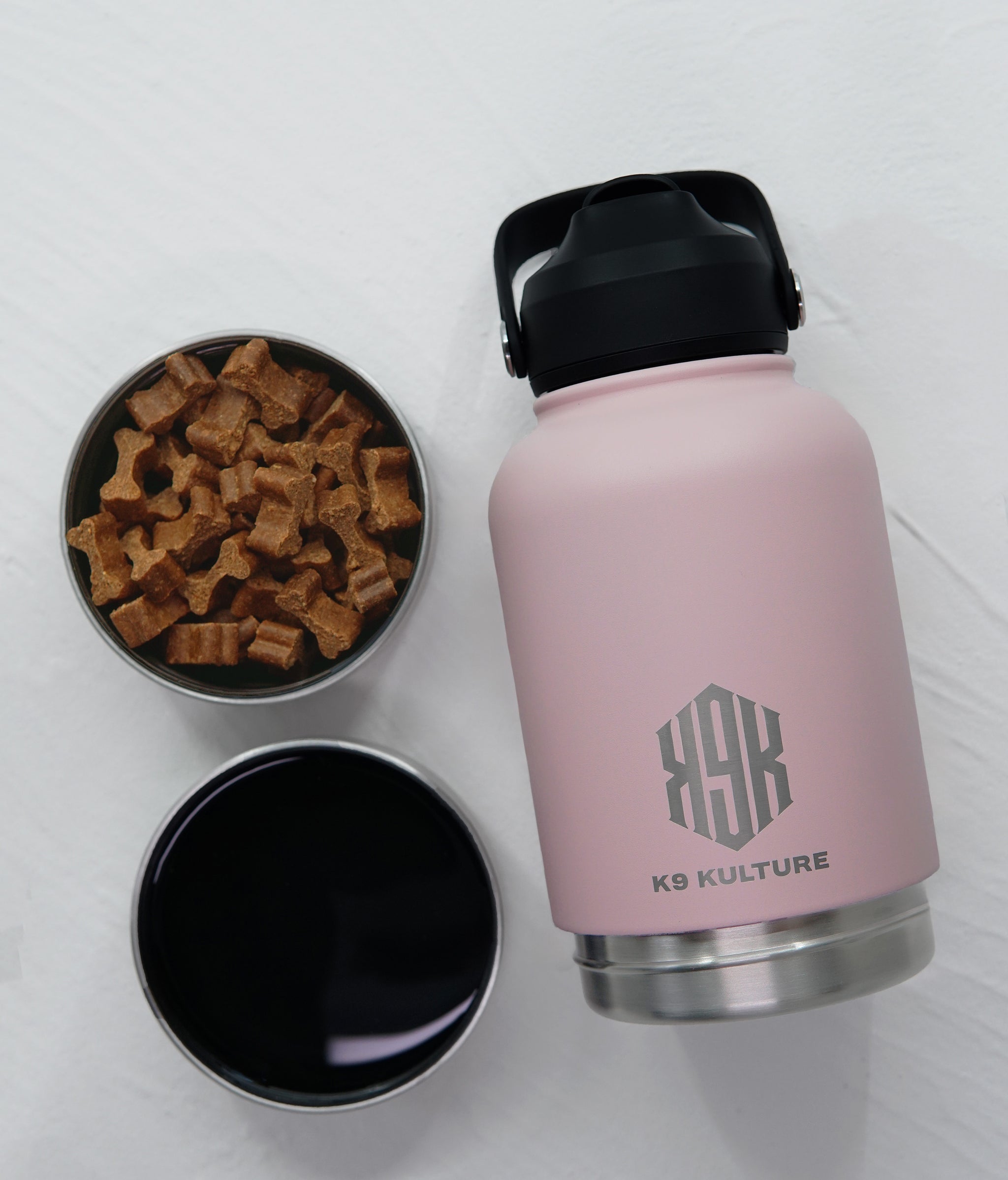 Pink ThermoACTIVE insulated dog water bottle displayed with dual compartments—one filled with water, one with treats.